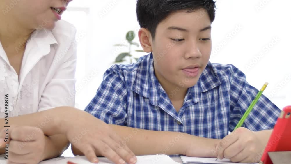 Young asian mother teaching son at home. Asian mother with son doing homework on table with smile face. Dolly shot 4K Young asian mother teaching son at home. Asian mother with son doing homework on table with smile face. Dolly shot 4K
