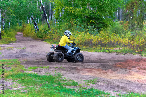 A young boy drives his quad on sandy ground