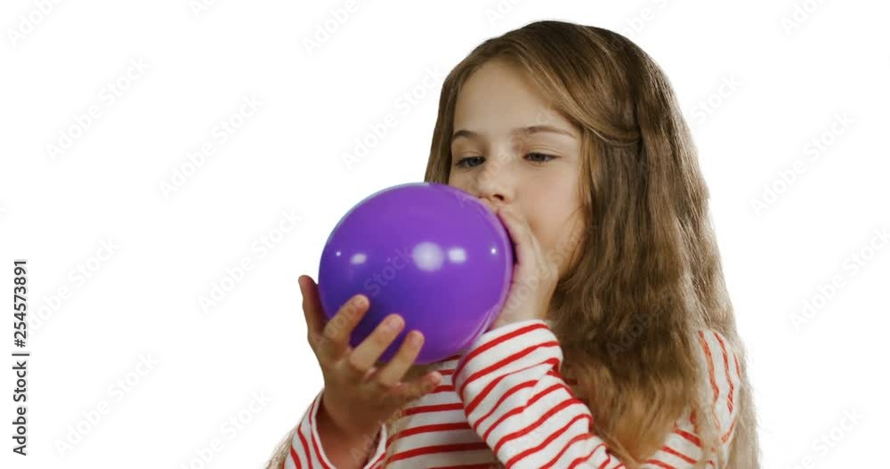 Close up of the blonde pretty small schoolgirl with a long hair inflating a balloon on the white screen background. Close up of the blonde pretty small schoolgirl with a long hair inflating a balloon on the white screen background.