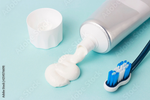 Toothpaste in tube and toothbrush on blue background. Dental hygiene concept.