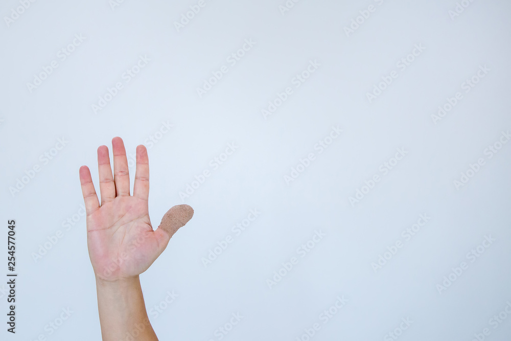 Injured painful finger with white bandage. Hand has been injured by the accident and showing thumb up.The thumb is wrapped with a bandage, which is first aid on a white background. Injured painful finger with white bandage. Hand has been injured by the accident and showing thumb up.The thumb is wrapped with a bandage, which is first aid on a white background.