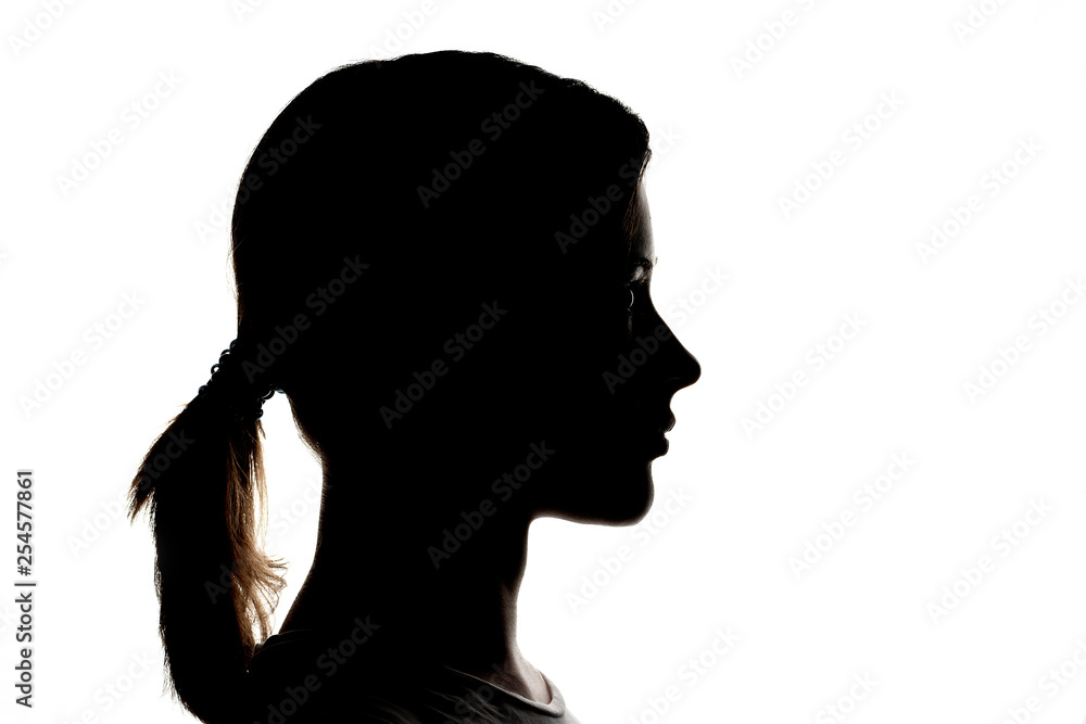 Dark silhouette profile of a young girl on a white background, concept of anonymity