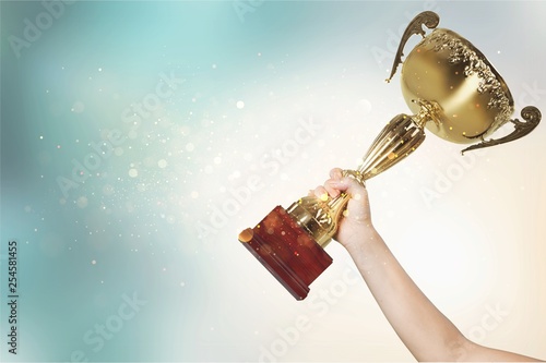 Hands holding golden trophy on a light background
