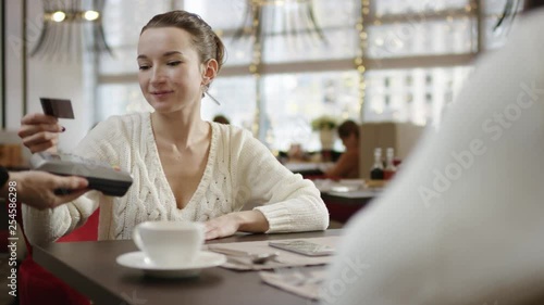 Young woman paying for lunch in a cafe with a credit card