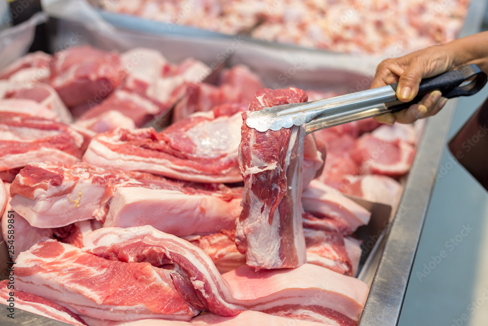 Consumer selecting fresh and clean pork chop  in supermarket