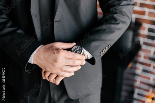 Close up of businessman's hands in black suite, adjusting wristwatch, time is money concept, waiting concept , business concept