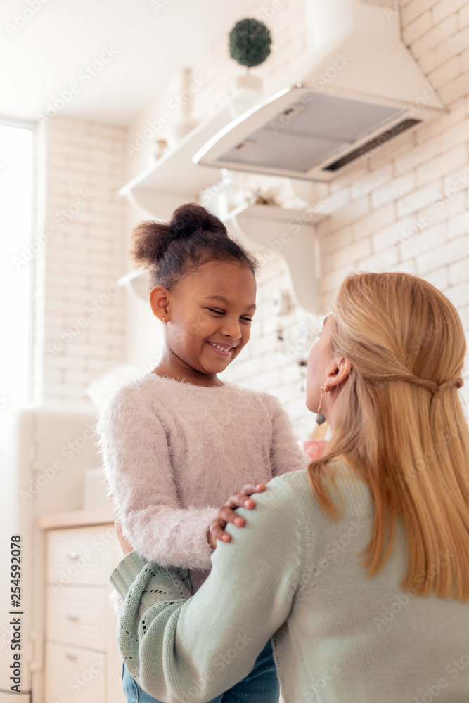 Woman hugging her foster child standing in the kitchen Woman hugging her foster child standing in the kitchen
