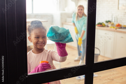 Принти на полотні Little cute girl smiling while helping her mother with cleaning