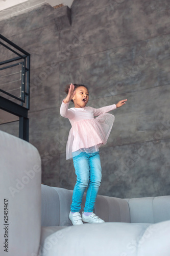 Fototapeta Naklejka Na Ścianę i Meble -  Cheerful little girl laughing while having fun and jumping