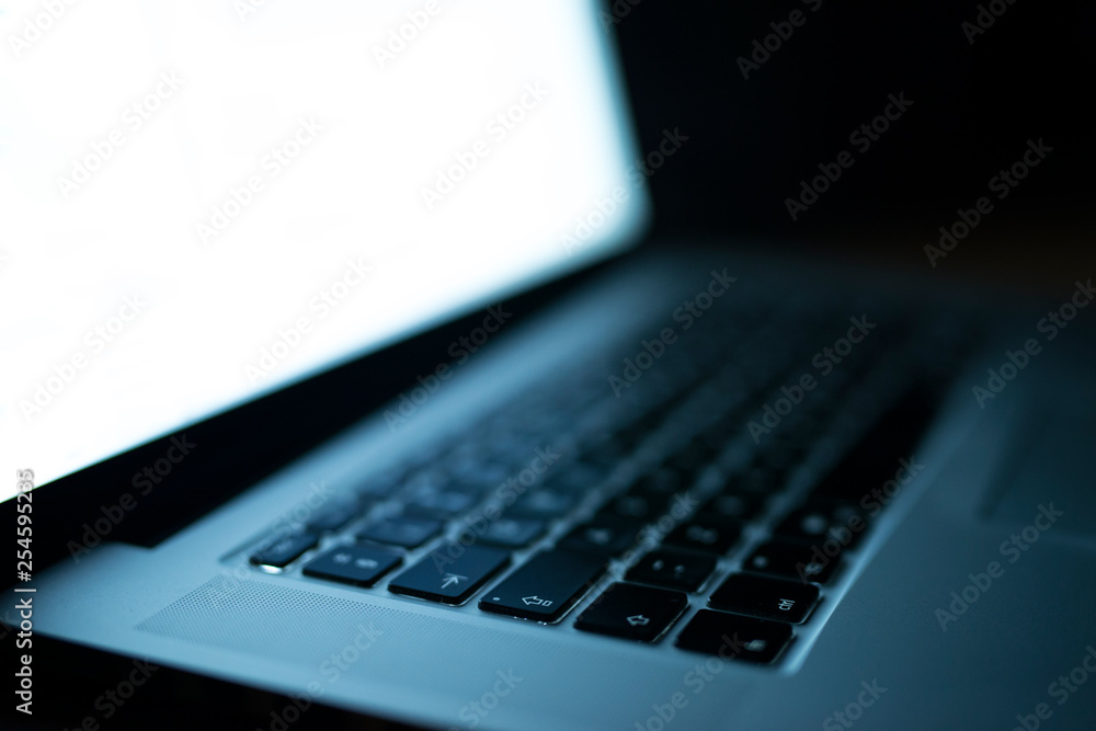 Photo of an open laptop computer with white screen display. Focus on keyboard buttons. Side view. Photo of an open laptop computer with white screen display. Focus on keyboard buttons. Side view.