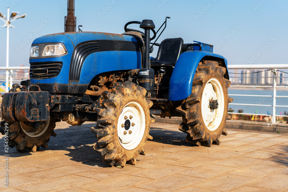 Blue tractor on the background of an empty field and a clear blue sky Blue tractor on the background of an empty field and a clear blue sky