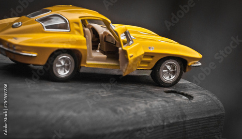 Toy car model Corvette Sting Ray 1963 year. Yellow color. Side view. Opened door. Close-up. Macro. Isolated. © Iurii Korolev