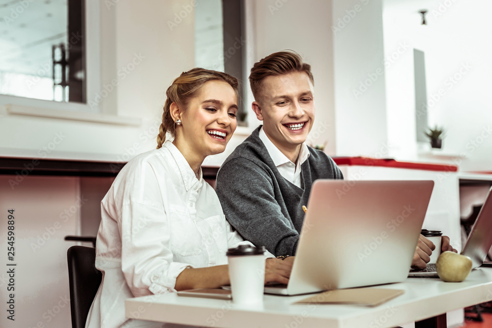 Laughing good-looking friends sitting close to each other