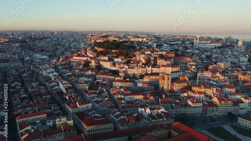 Aerial view; drone flight forward to the ancient building with brown rooftops; sunset time in Lisbon; beautiful winter evening in Portuguese capital; Alfama oldest historic district; view from above