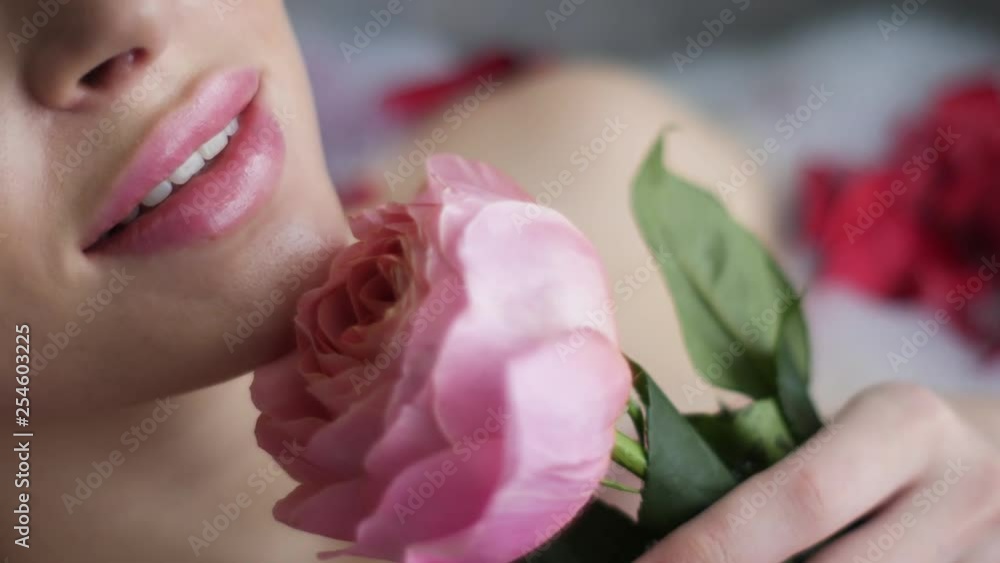portrait of a sexy woman lying in the bathroom with foam and holding a pink rose portrait of a sexy woman lying in the bathroom with foam and holding a pink rose