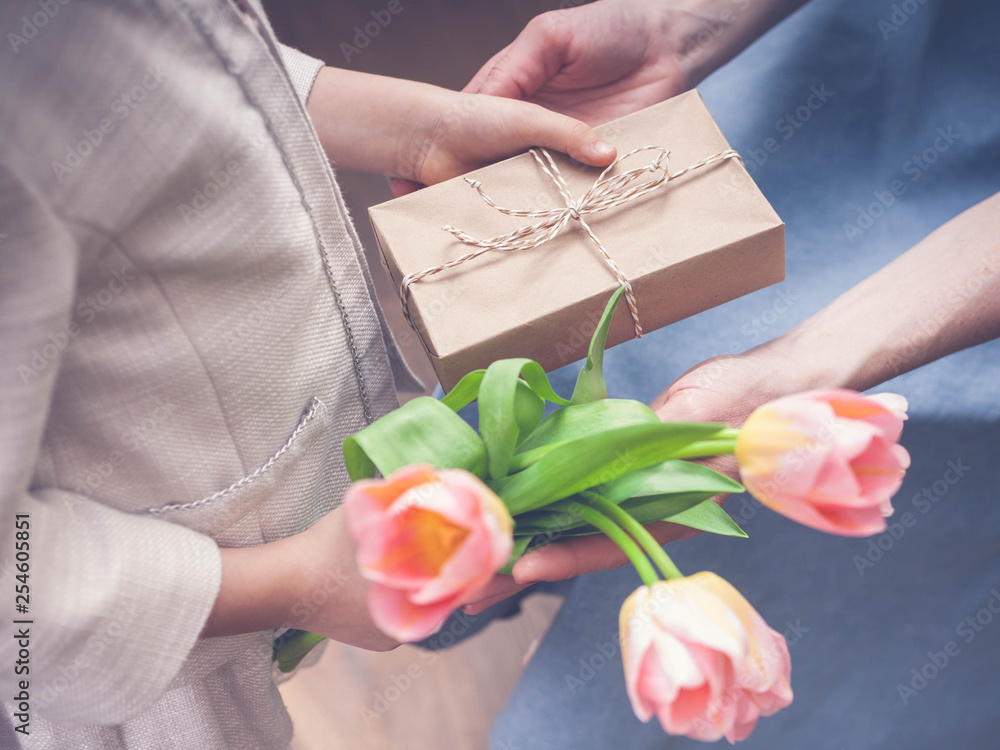 Happy Mother's Day. Little girl congratulates mom and gives a gift and flowers tulips. Toning. Selective focus