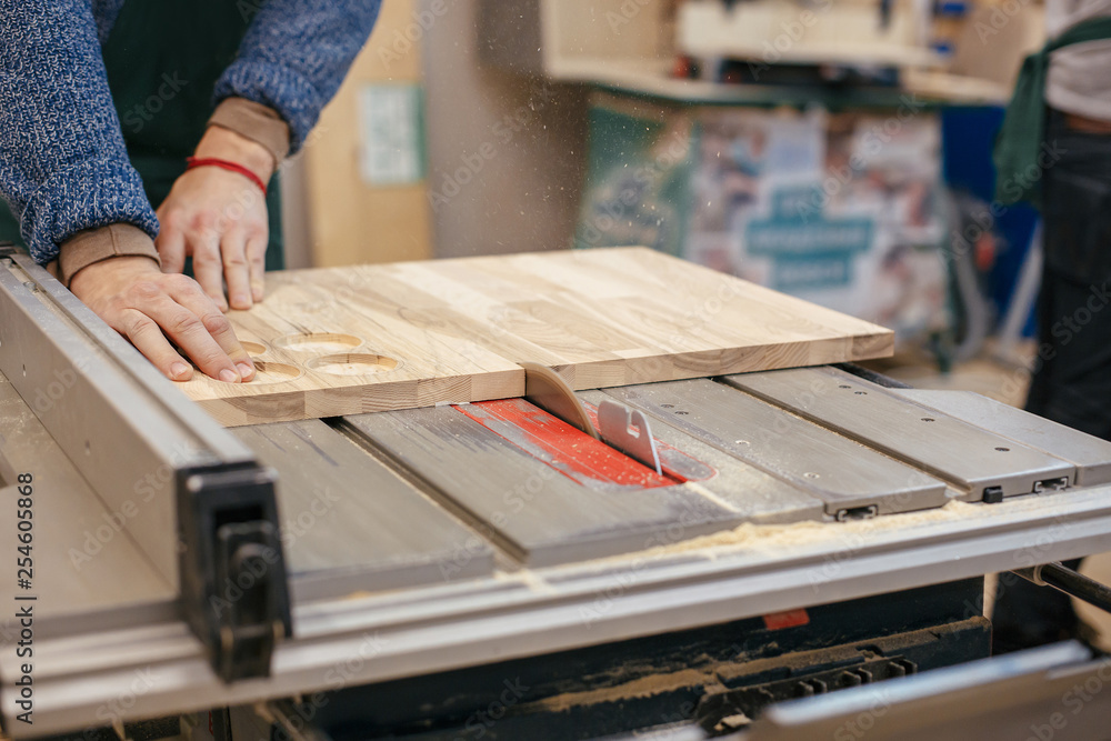 Hands of a professional joiner carpenter saw the gloss in half using a saw. Concept of dangerous hard work Hands of a professional joiner carpenter saw the gloss in half using a saw. Concept of dangerous hard work