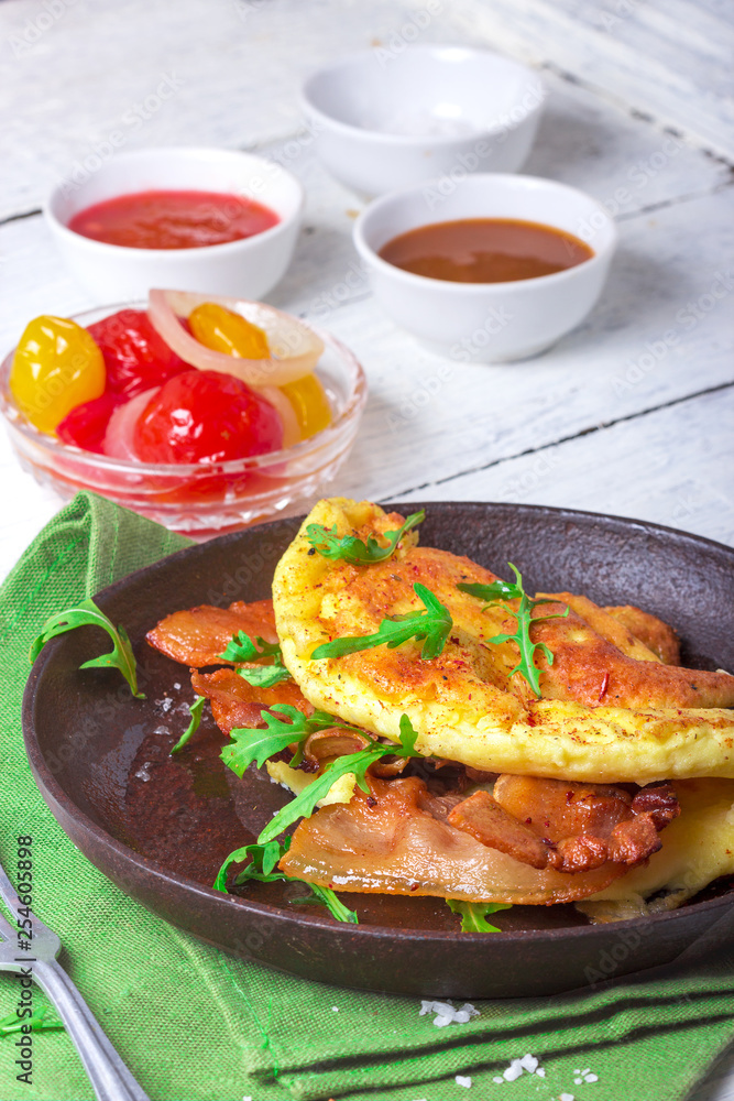 Delicious bacon omelette with arugula and colorful pickled tomatoes Delicious bacon omelette with arugula and colorful pickled tomatoes