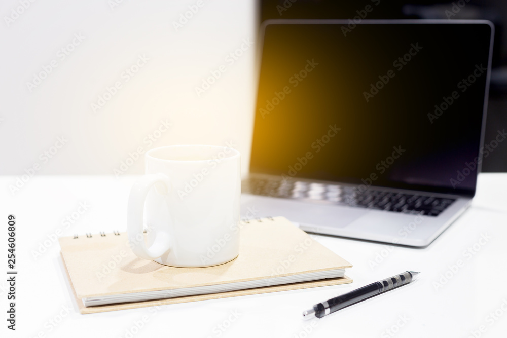 Workspace laptop with coffee cup and notebook on background ,computer screen graphics and charts Workspace laptop with coffee cup and notebook on background ,computer screen graphics and charts