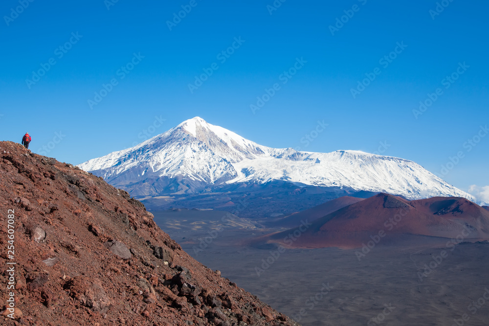 A tourist photographer at the top of the mountain takes pictures of the landscape of volcanoes  Tolbachik. Kamchatka
