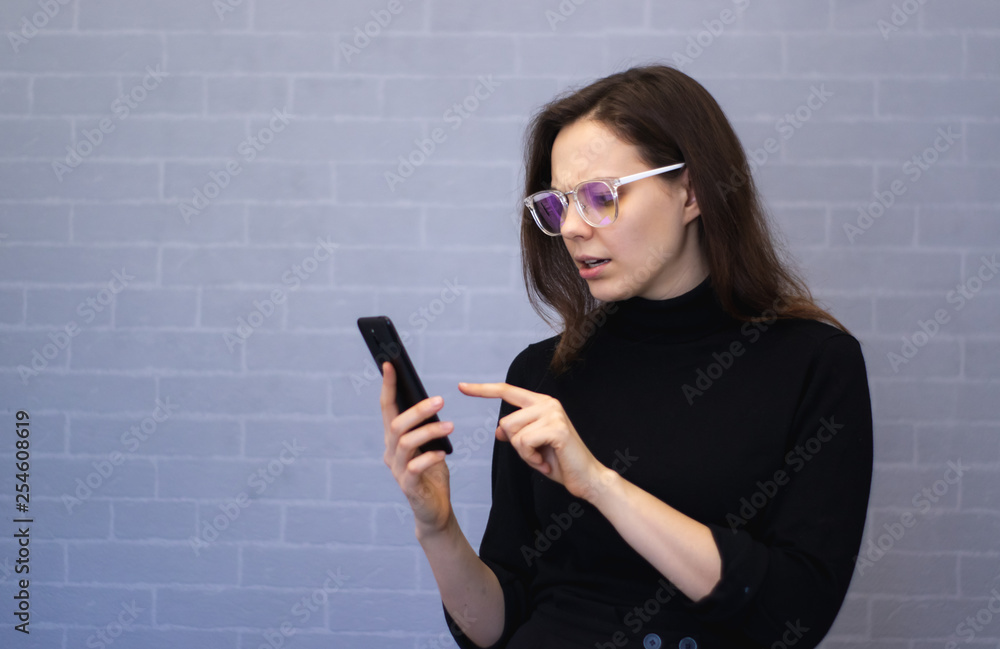 Dissatisfied young woman holding the phone on hand Dissatisfied young woman holding the phone on hand