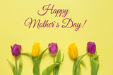 Yellow and purple flowers tulips in a bouquet on a yellow background and the inscription happy mother's day, a festive spring background greeting card