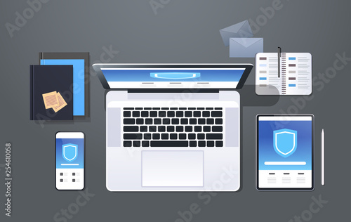 data protection internet security shield privacy information safety concept top angle view desktop laptop tablet smartphone screen secured access office stuff horizontal