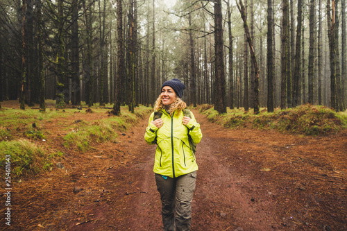Cheerful beautiful caucasian middle age woman doing trekking outdoor activity in the forest ina rainy day - adventure lifestyle for people love freedom and independence - beautiful nature concept © simona