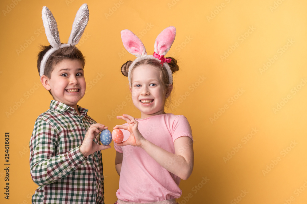 a boy with a girl with bunny ears hold Easter eggs in his hands