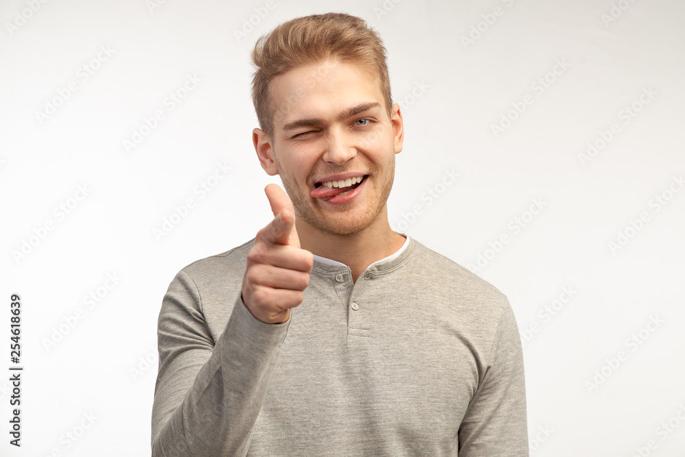 Cheerful unshaven male points at you, has happy expression, bristle, expresses his choice. Man does finger gun gesture. Isolated on white background in studio Cheerful unshaven male points at you, has happy expression, bristle, expresses his choice. Man does finger gun gesture. Isolated on white background in studio