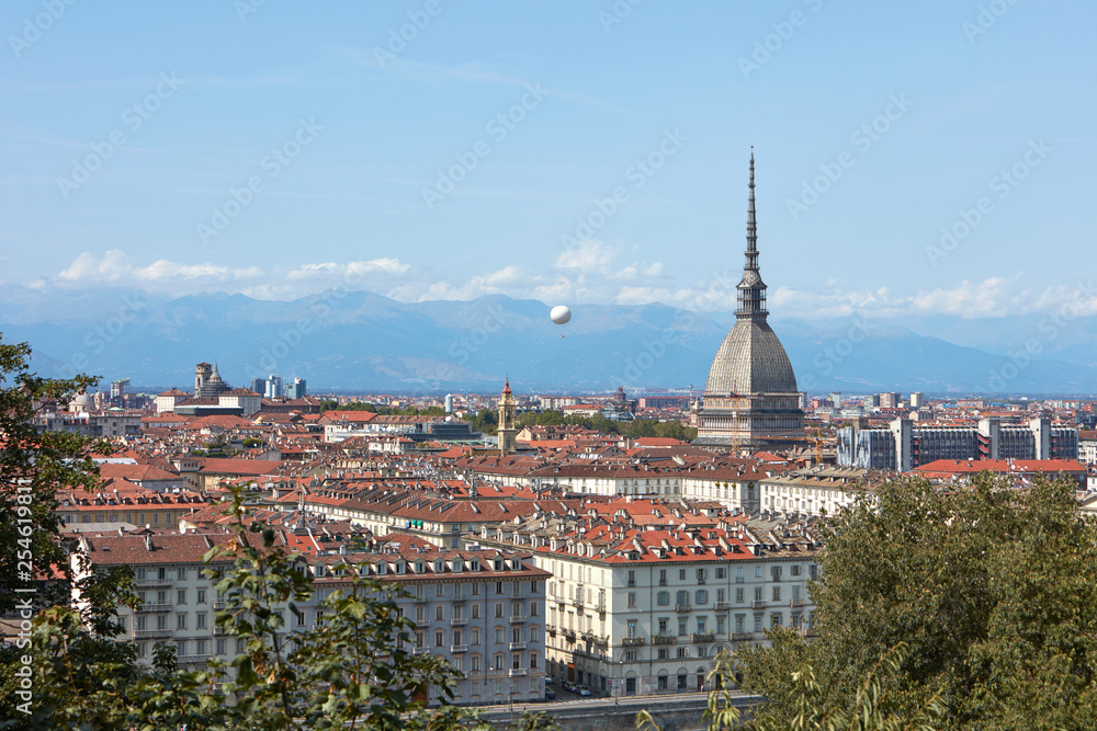 Turin rooftops view, Mole Antonelliana tower and hot air balloon in a sunny summer day in Italy