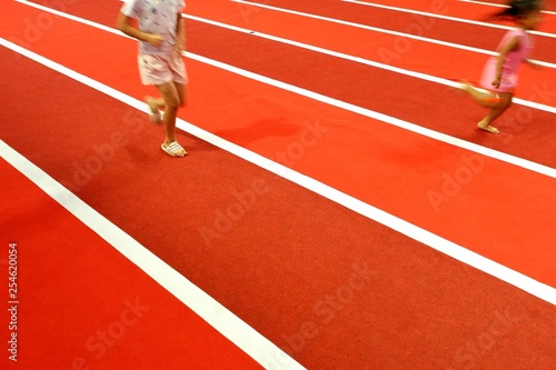 Blur motion of little girls running on colorful indoor atheltic running tracks in playground area of shopping mall