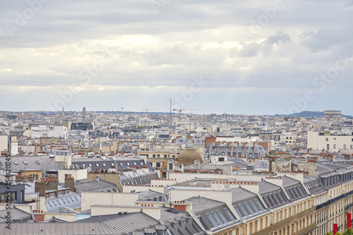 Paris rooftops view and city skyline in a cloudy day with sun beam in France