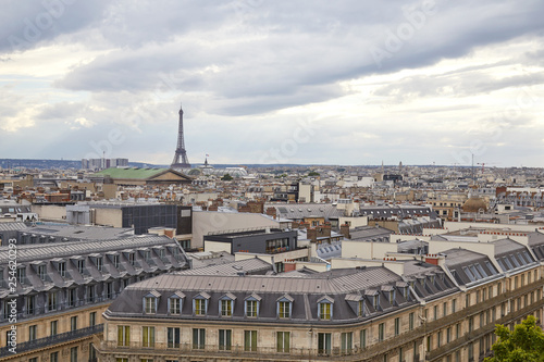 Paris rooftops view and Eiffel Tower in a cloudy day, horizon in France