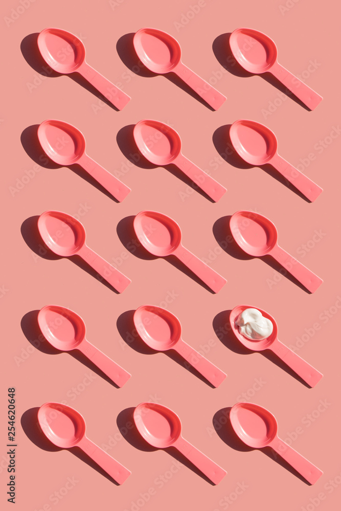 Pink plastic spoons in a row with a sample of cream one of it. Abstract conception. Pink plastic spoons in a row with a sample of cream one of it. Abstract conception.