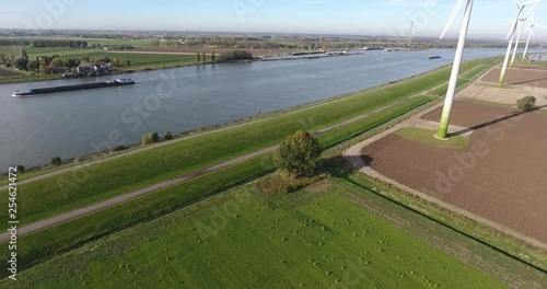 Aerial view of wind power turbines by river with boats silling photo