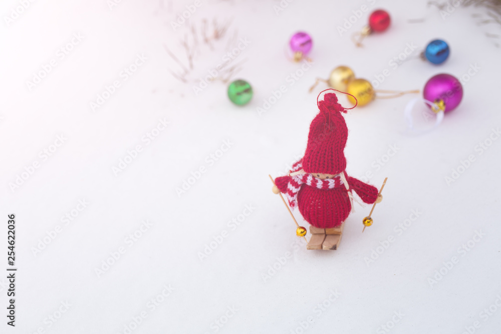 Winter photo with Christmas decorations for pine tree. Knitted snowman toy girl standing on the ski in the forest. Happy holidays ornaments postcard. Snowy weather. Winter photo with Christmas decorations for pine tree. Knitted snowman toy girl standing on the ski in the forest. Happy holidays ornaments postcard. Snowy weather.