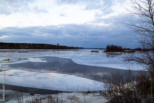 Fototapeta Naklejka Na Ścianę i Meble -  The descent of ice in the spring on the river in March is a natural phenomenon against the sky and clouds in the evening.