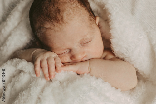 Adorable newborn baby is sleeping on his belly lay on beige blanket. Beginning of life and happy childhood concept. Новорожденный ребенок спит на светлом одеяле.