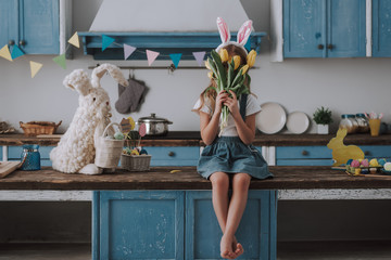 Happy girl hiding by yellow tulips bunch