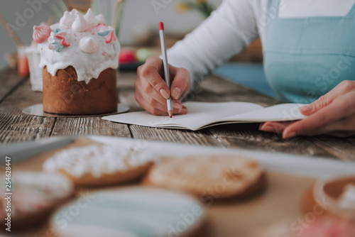 Young woman writing in copybook on kitchen table