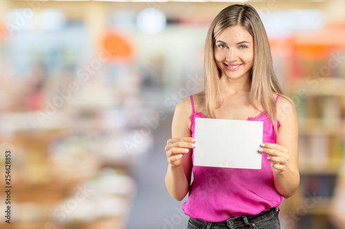 Happy smiling beautiful young woman in pink smart casual clothing showing blank signboard or copyspace for slogan or text