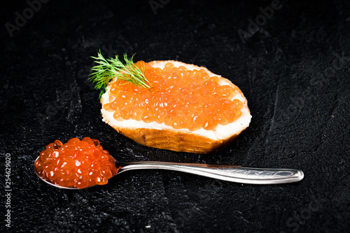 Red caviar with bread on black