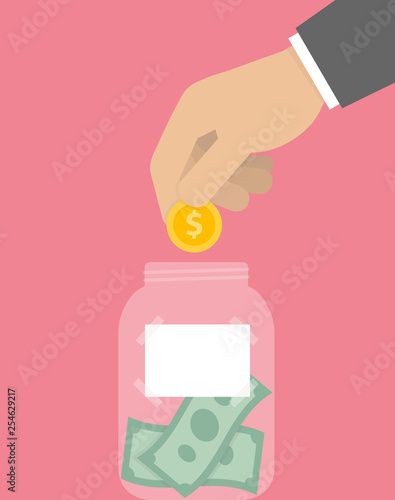 Hand putting golden coin into the money jar with blank label