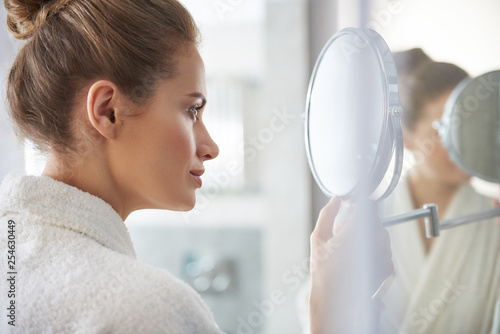 Confident lady looking at round vanity mirror