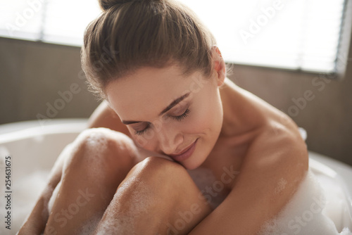 Relaxed lady put head on knees while enjoying bath