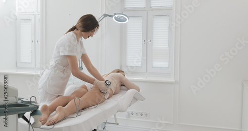 Hardware figure correction. Ultrasound cavitation body contouring treatment. Beautiful woman getting anti-cellulite and anti-fat therapy in beauty salon photo