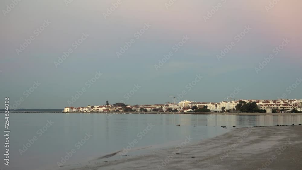 Beautiful and calm coast at the sunset with the background of a small white city Beautiful and calm coast at the sunset with the background of a small white city