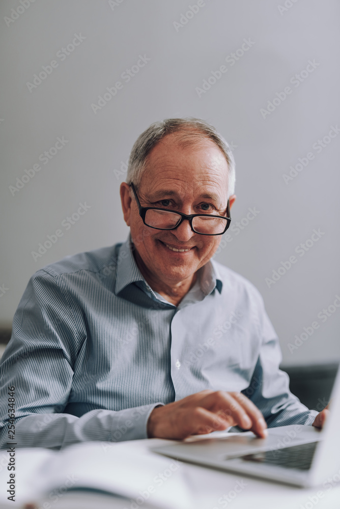 Joyful old man in glasses using modern laptop Joyful old man in glasses using modern laptop