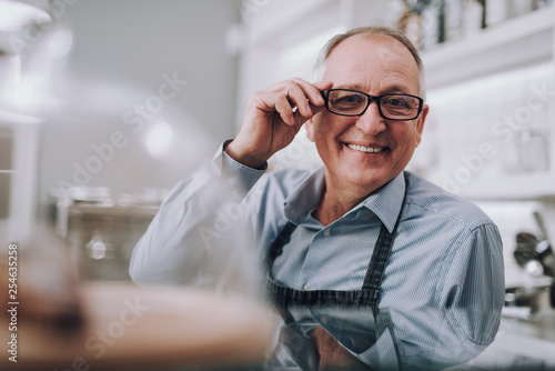 Cheerful gentleman touching frame of his eyeglasses